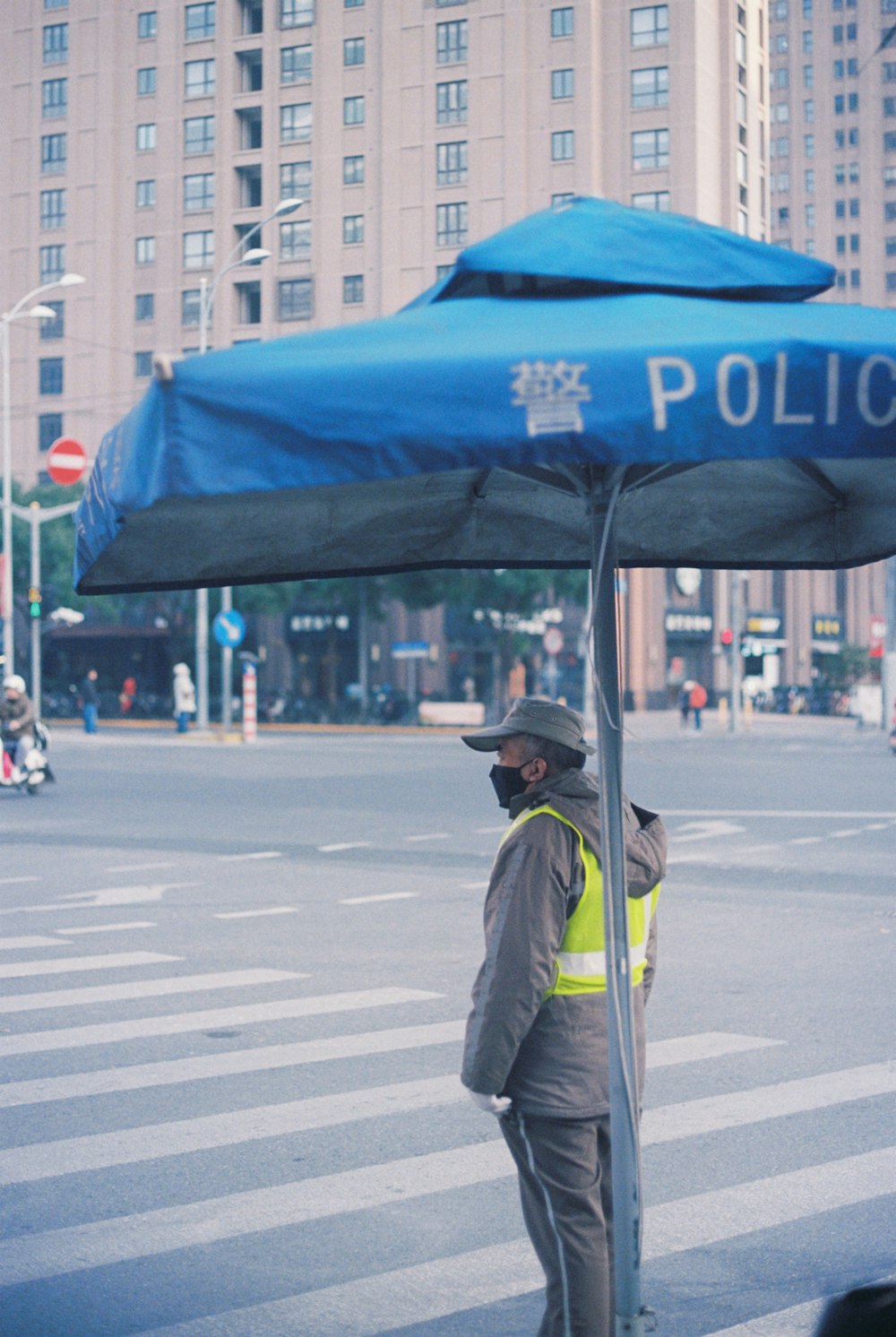 a police officer standing under a blue umbrella