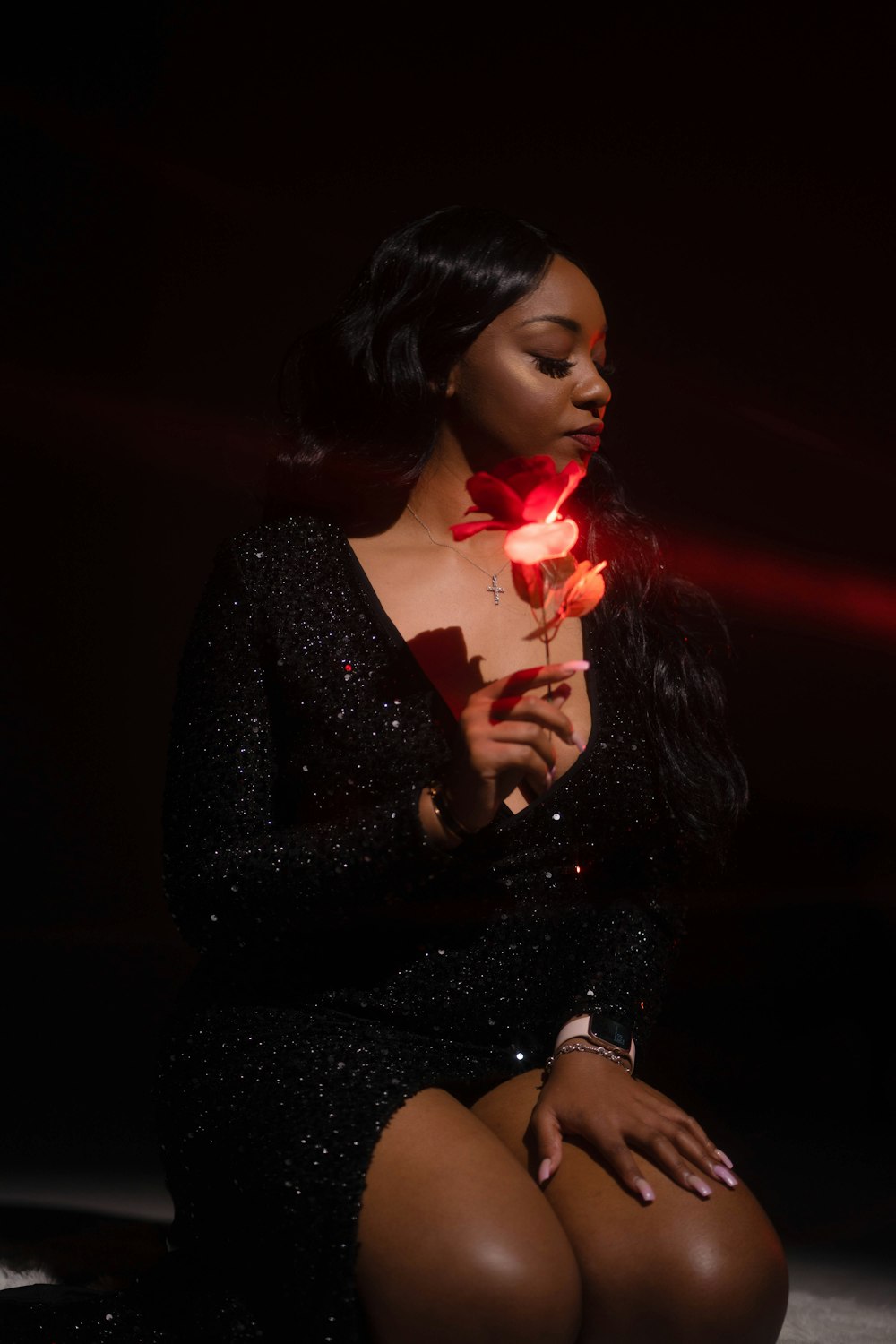 a woman in a black dress holding a rose