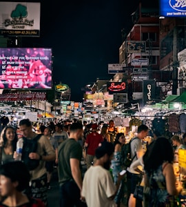 a crowd of people walking down a street next to tall buildings