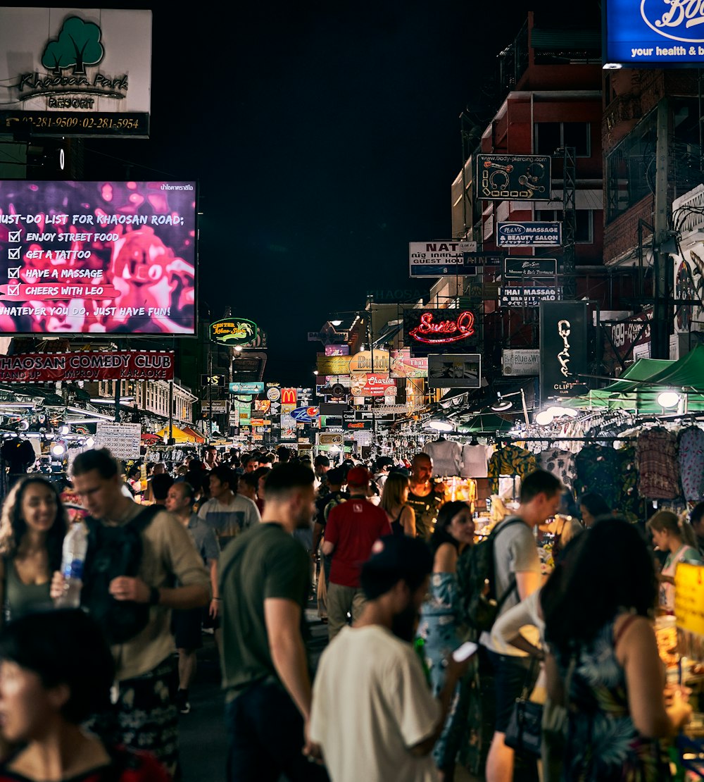 a crowd of people walking down a street next to tall buildings