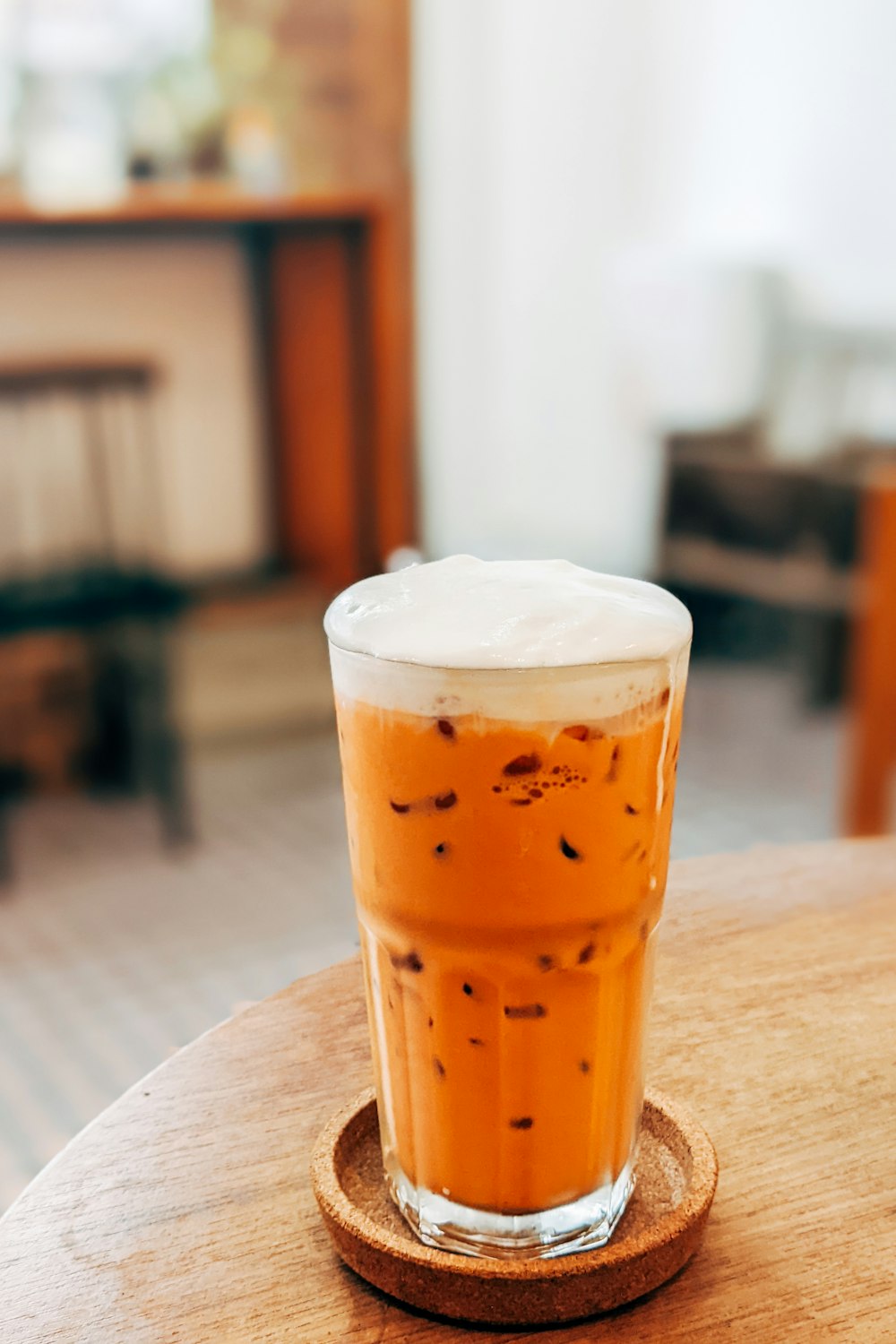 a glass of iced coffee sitting on top of a wooden table