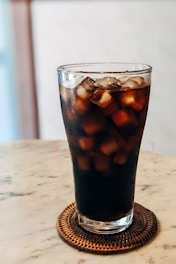 A vibrant glass of cola with a hint of traditional Pakistani spices on a rustic wooden table.