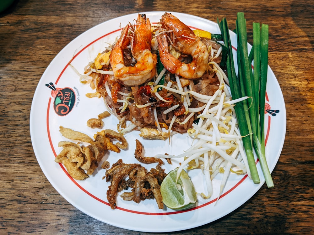 a plate of food with shrimp, noodles, and green onions