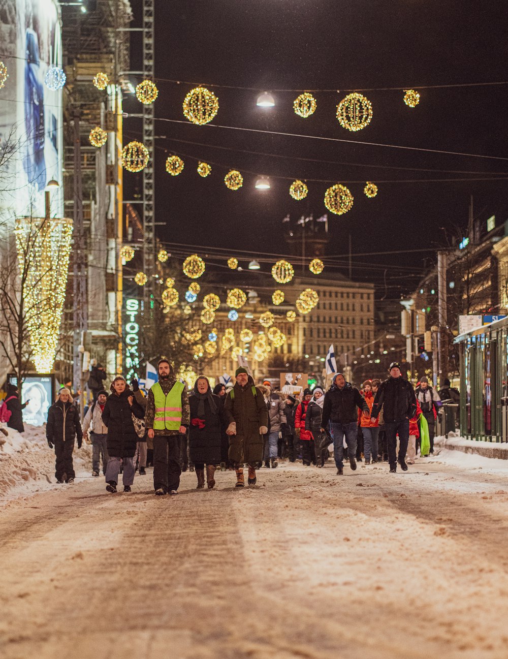 a group of people walking down a snow covered street