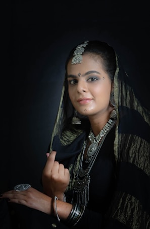 a woman wearing a veil and jewelry poses for a photo