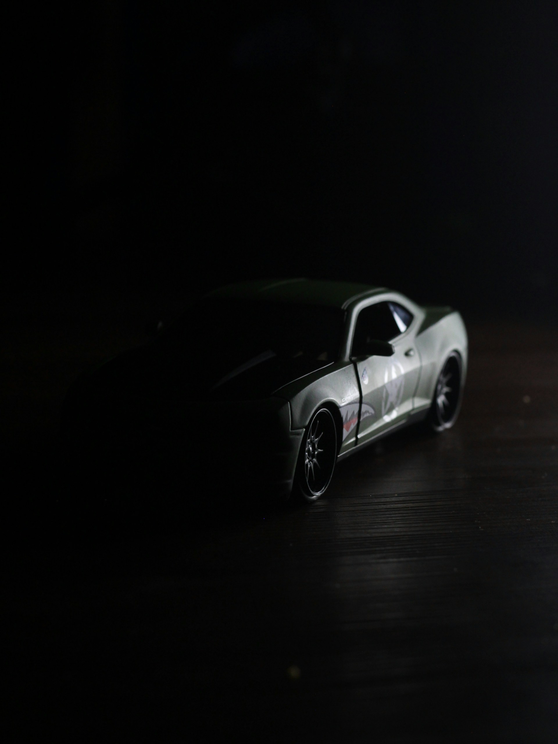 An artistic shot of a custom toy prototype in monochrome shades accented with deep purples, placed on a minimalist black background.