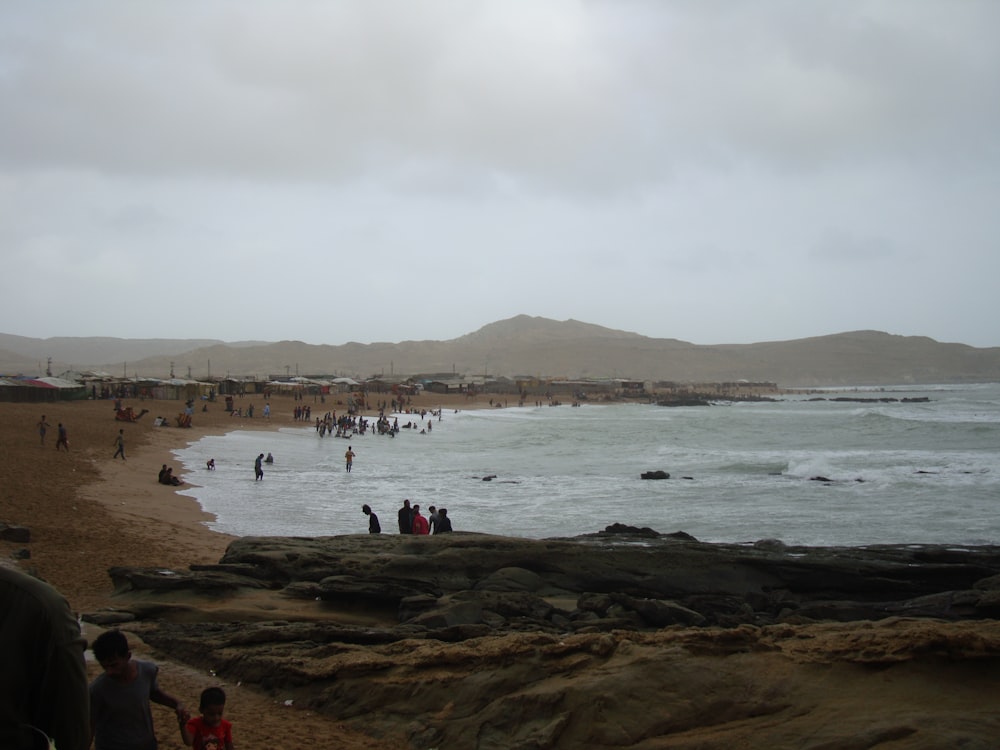 a group of people standing on top of a sandy beach