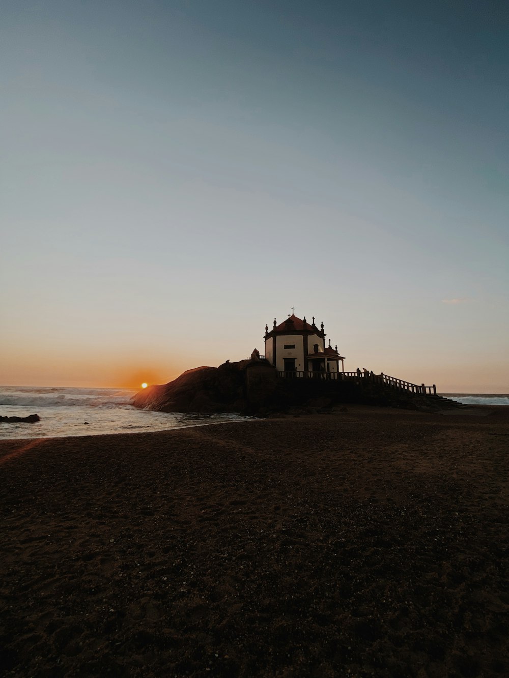 a small house sitting on top of a sandy beach