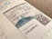 A close-up view of a Japanese immigration inspector's landing permission stamp on a passport page, featuring a document with text in both Japanese and English. The stamp includes the date of entry and validity, with visible QR codes and security features embedded in the design.