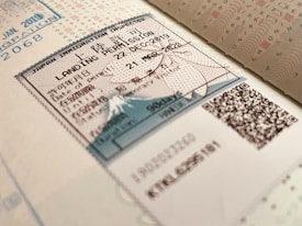 A close-up view of a Japanese immigration inspector's landing permission stamp on a passport page, featuring a document with text in both Japanese and English. The stamp includes the date of entry and validity, with visible QR codes and security features embedded in the design.