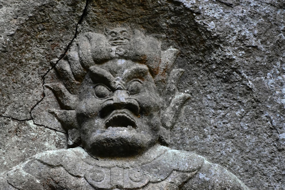 a close up of a statue on a stone wall