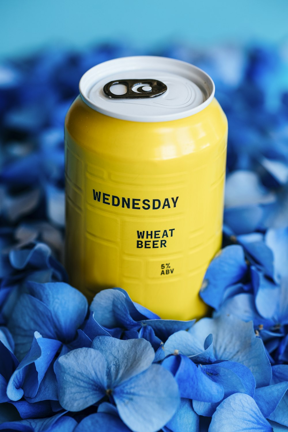 a can of beer sitting on top of blue flowers