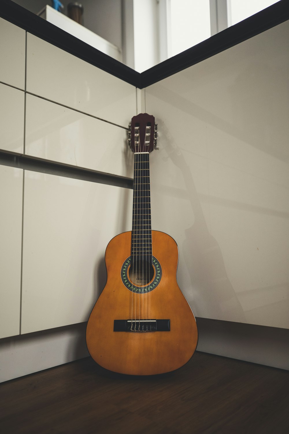 a guitar sitting on the floor in front of a mirror