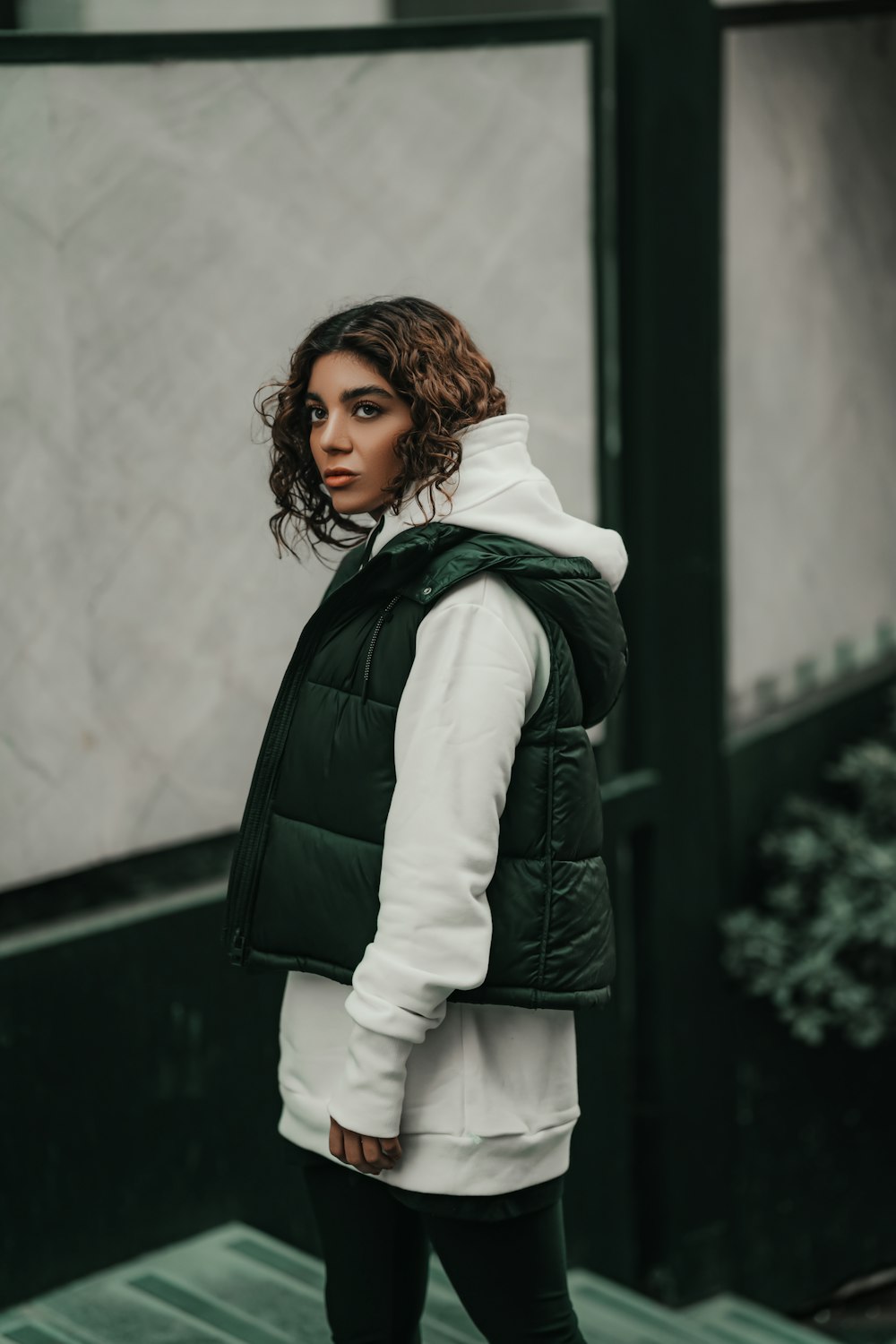 a woman wearing a green vest and black leggings