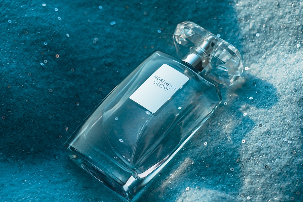 Una botella de colonia sentada sobre una alfombra azul