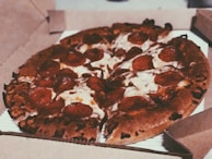 A freshly baked pepperoni pizza with melted cheese and crispy edges is placed inside an open cardboard pizza box.