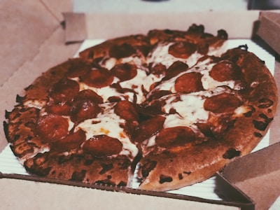 A steaming hot pizza being placed into a delivery bag.