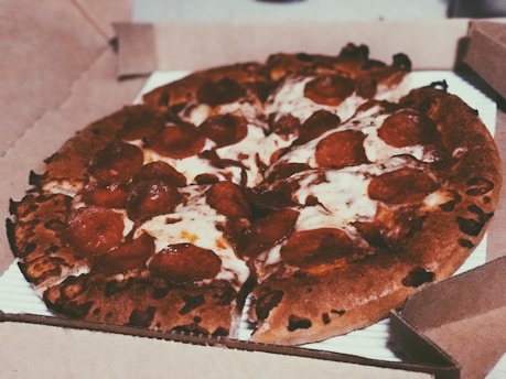 A delivery driver handing over a fresh pizza box at a customer's door.