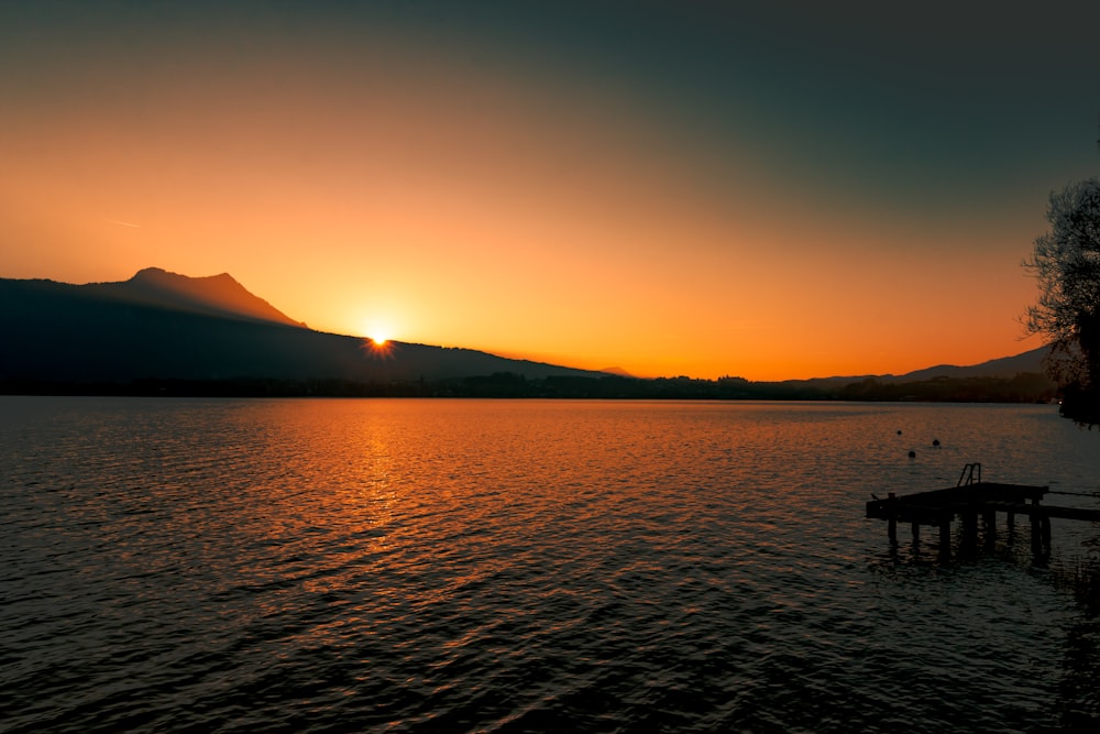 a sunset over a lake with a dock in the foreground