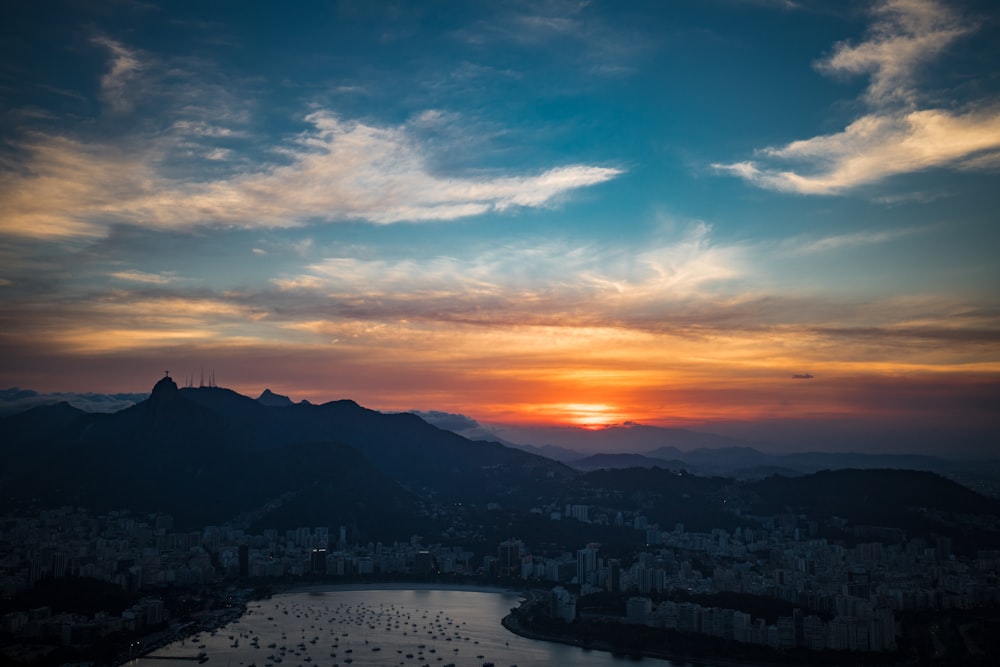 the sun is setting over a city and a body of water