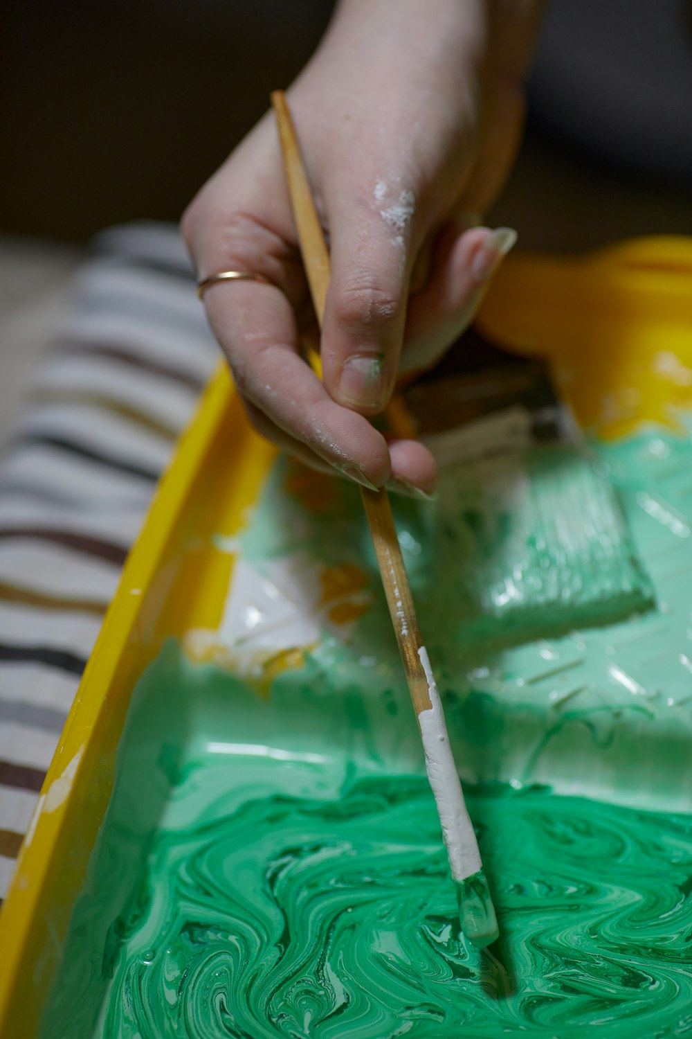 a person holding a paintbrush in a yellow container