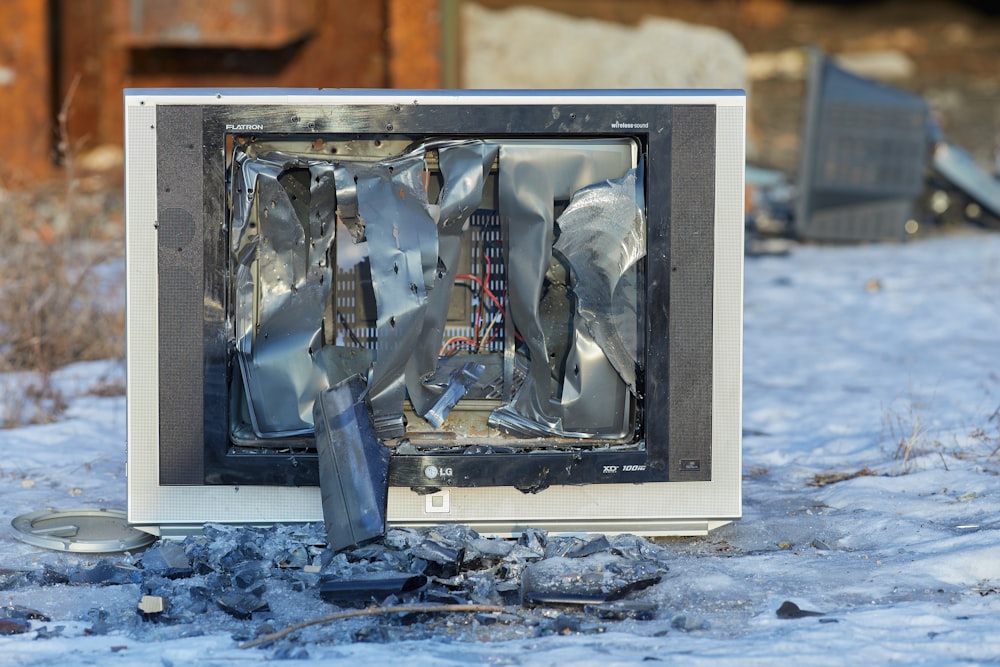 a broken television sitting on top of snow covered ground