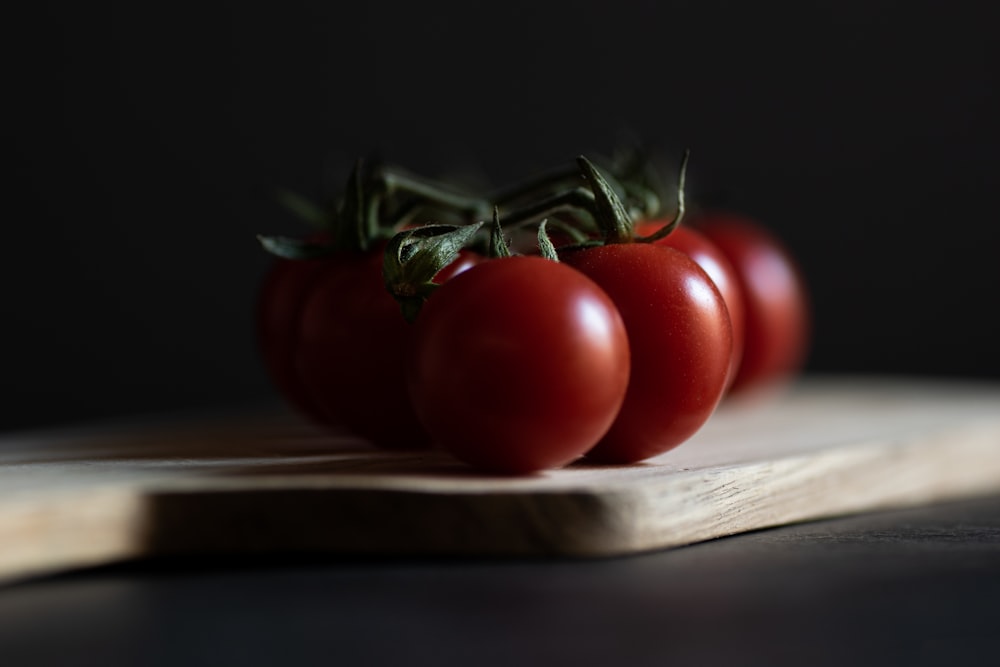 three tomatoes sitting on top of a cutting board