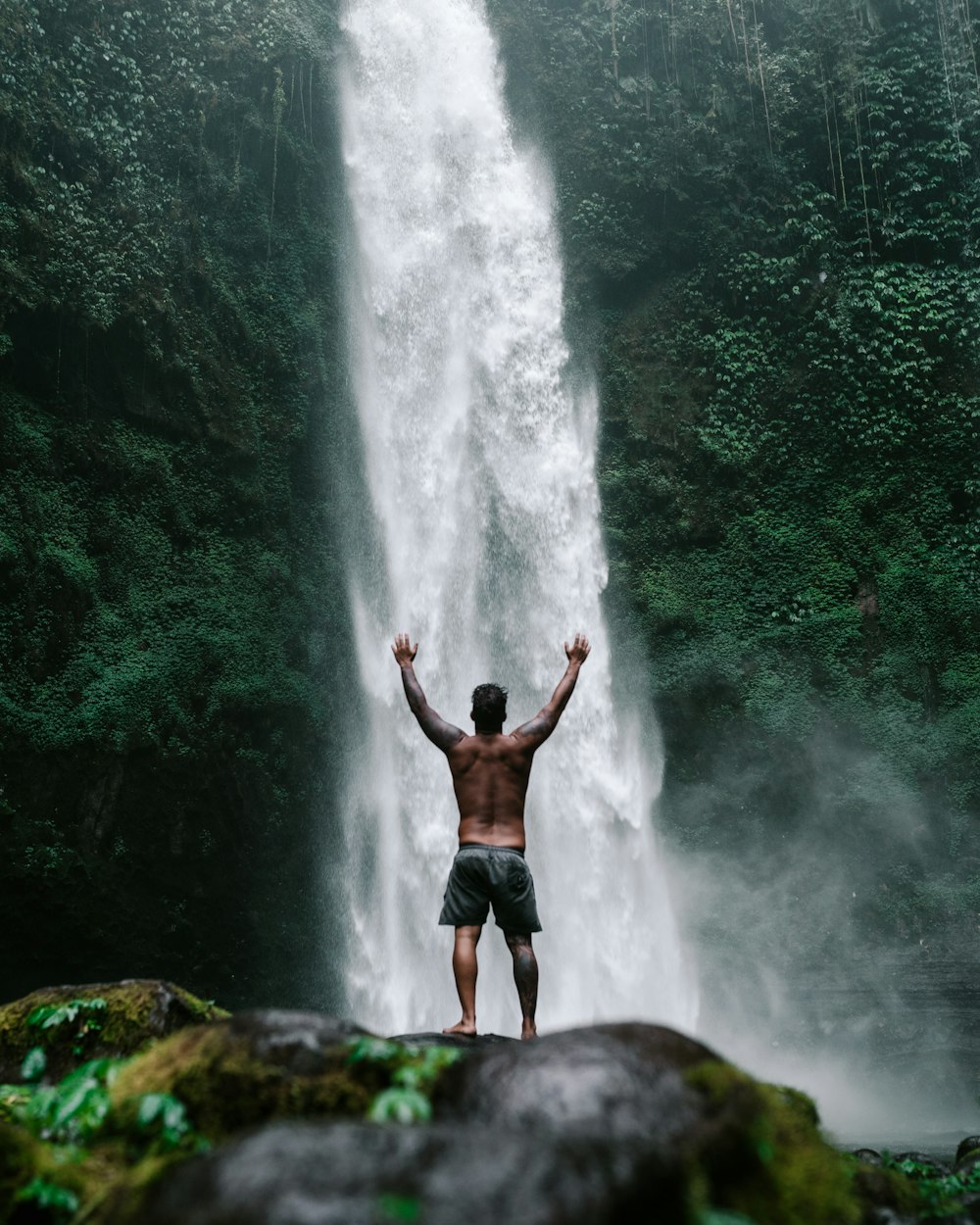 a man standing in front of a waterfall