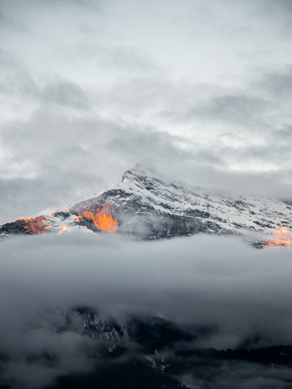 Una montaña cubierta de nubes y luces naranjas