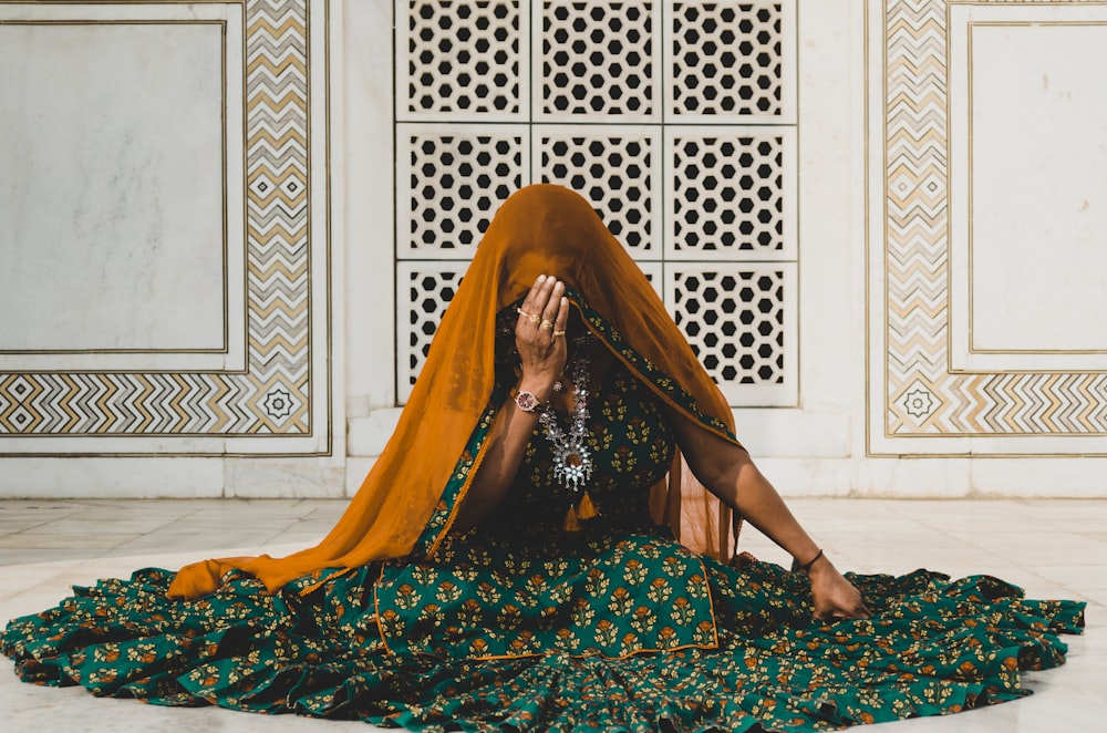a woman sitting on the floor covering her face with her hands
