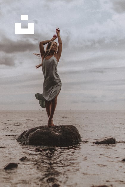 A woman standing on top of a rock in the ocean photo – Free Grey