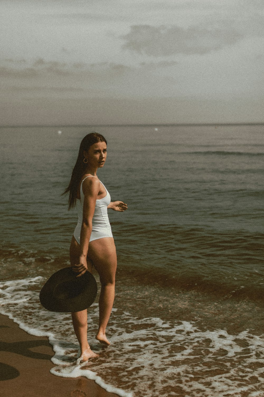 a woman standing on a beach next to the ocean