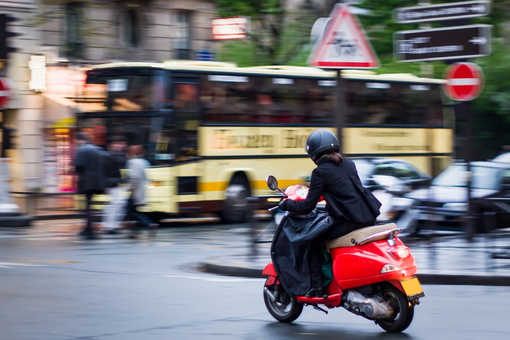 a man riding a red scooter down a street