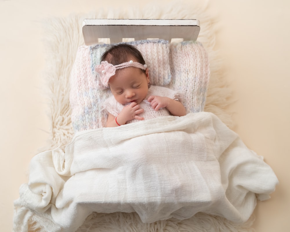 un bébé dort dans une couverture blanche