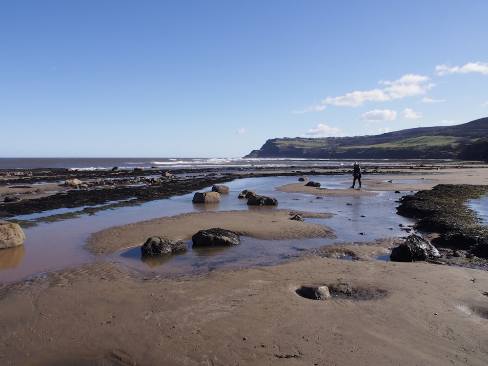 a man standing on a beach next to a body of water