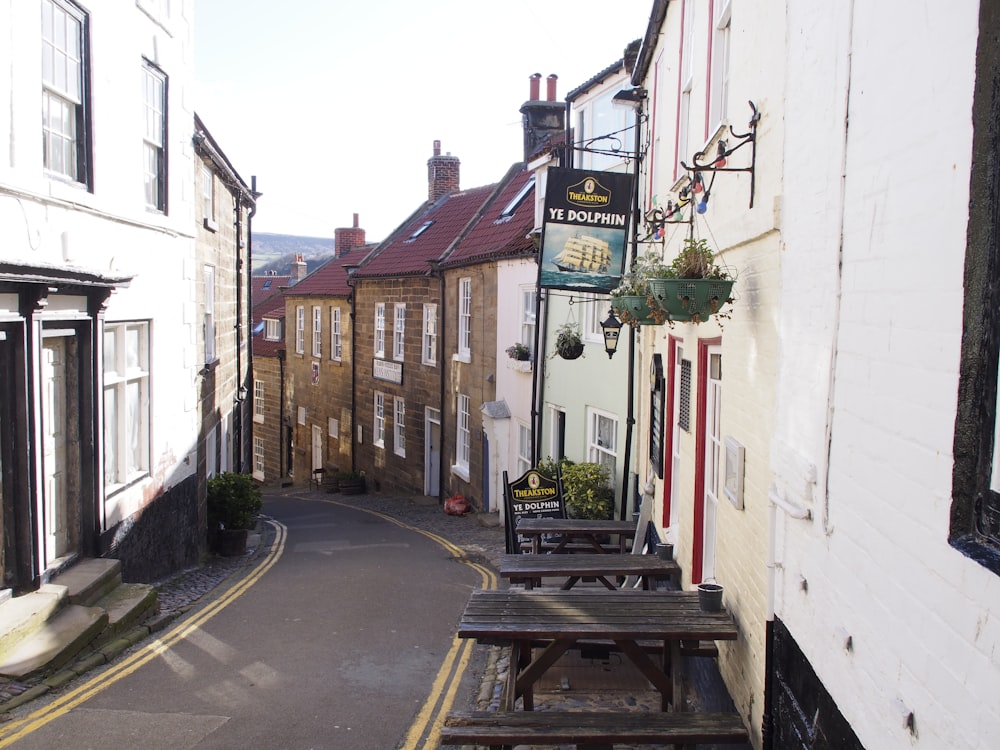 a narrow street with tables and benches on the side of it