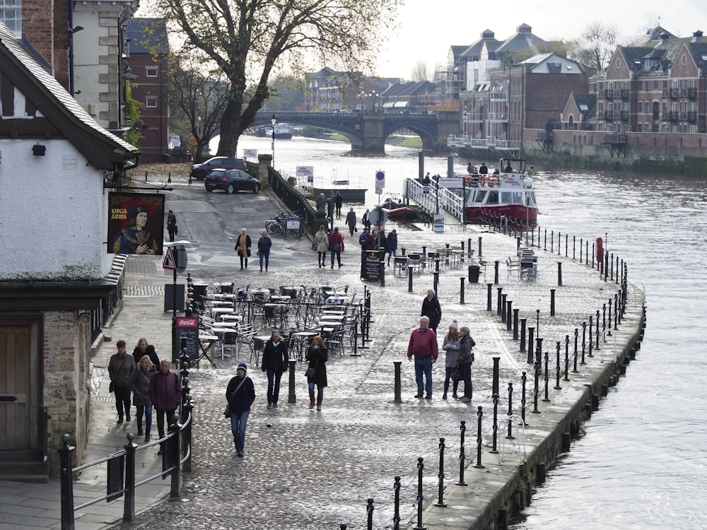 a group of people walking down a street next to a river