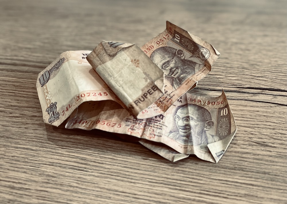 a pile of indian currency sitting on top of a wooden table