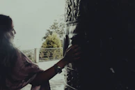 A gentle hand playing a wooden drum surrounded by ferns and vines.