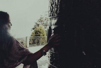 A serene forest clearing with a woman playing a shamanic drum near a fire circle.