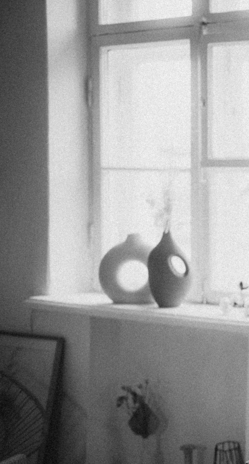 a black and white photo of a vase on a window sill