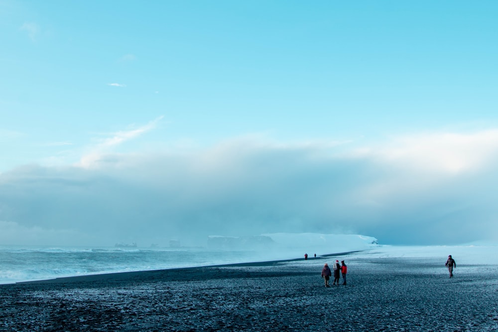 a group of people standing on top of a beach