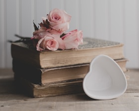a stack of books with pink roses on top of it
