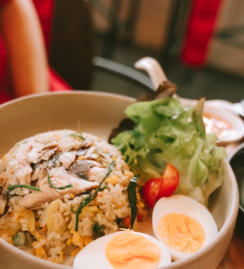 a bowl of rice, eggs, and vegetables on a table