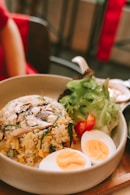 a bowl of rice, eggs, and vegetables on a table