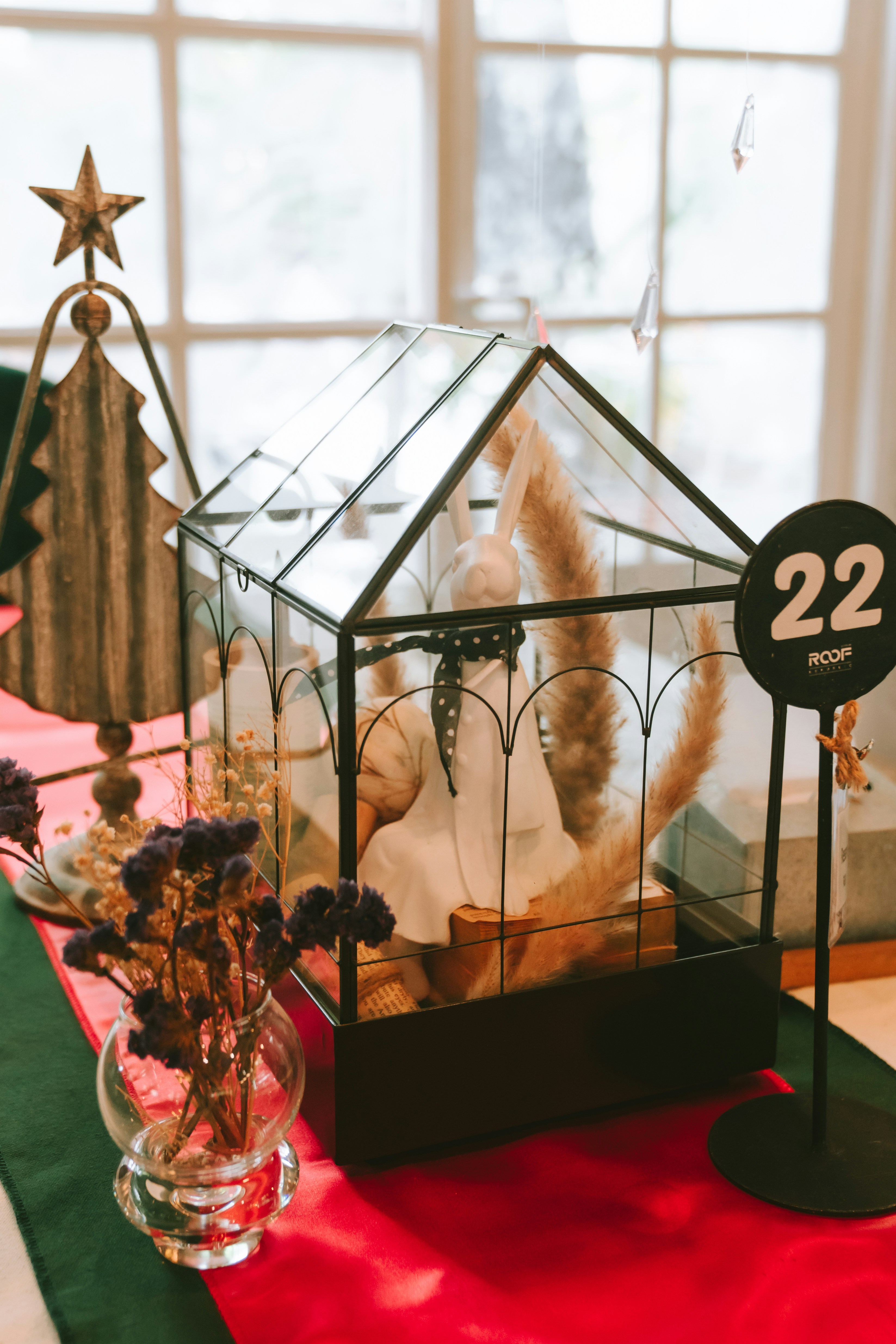 a glass house on a table with flowers in a vase