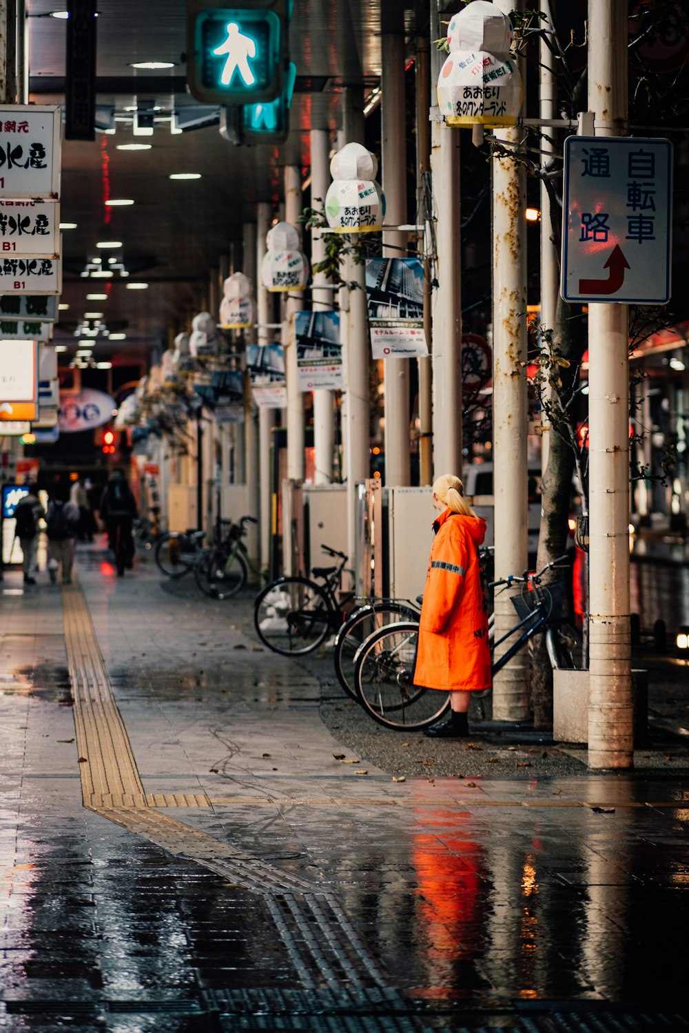 a person in an orange jacket standing on a sidewalk