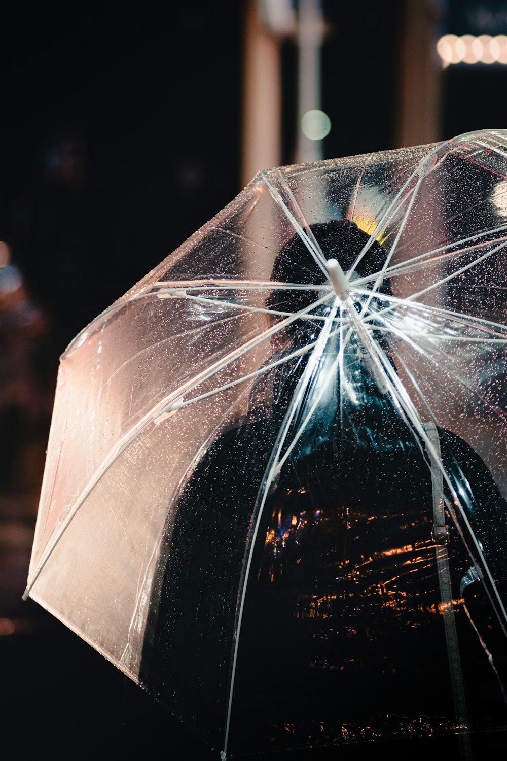 a person holding a clear umbrella at night