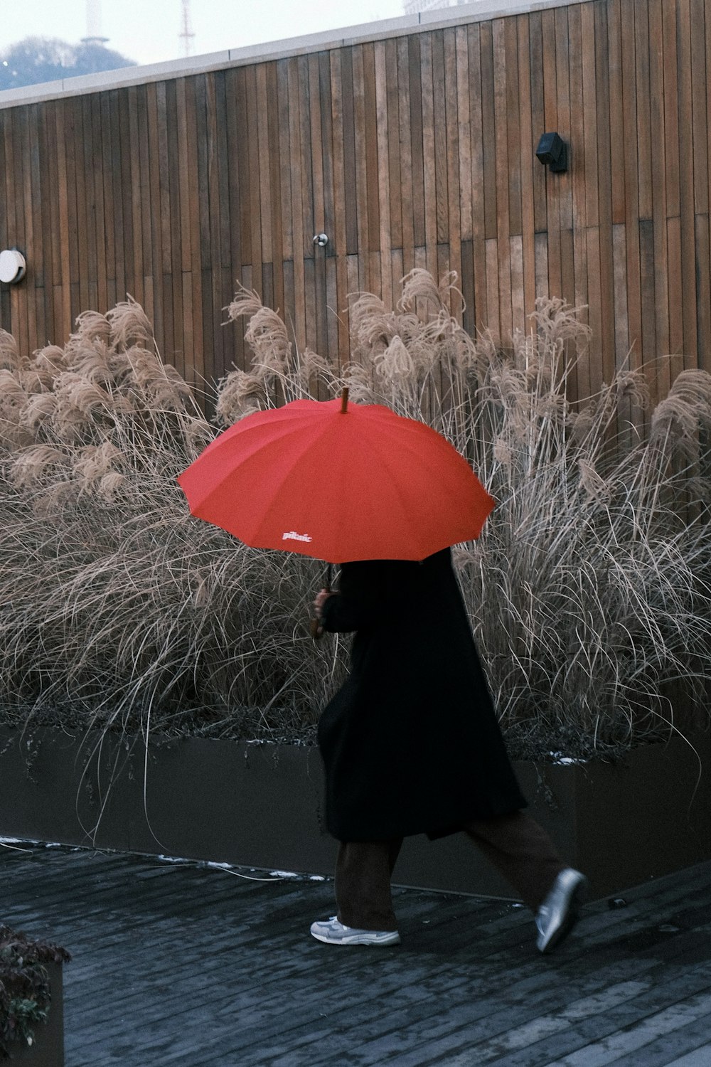 a woman walking down a street holding a red umbrella
