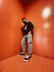 A close-up of a person wearing a sleek black nmsd concepts hoodie, standing confidently against an urban graffiti wall.